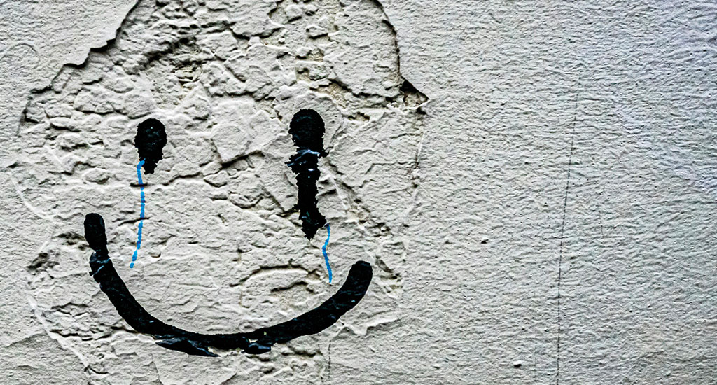 illustration d'un graffiti représentant un smiley qui pleure et sourit en même temps